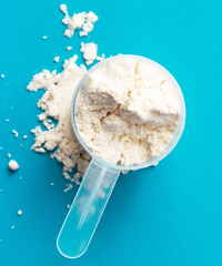 Clear plastic scoop filled with protein powder on a blue background