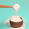 Cup of white powder with a wooden spoon on a light blue background