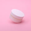 Small white container with pink lid on a light pink background